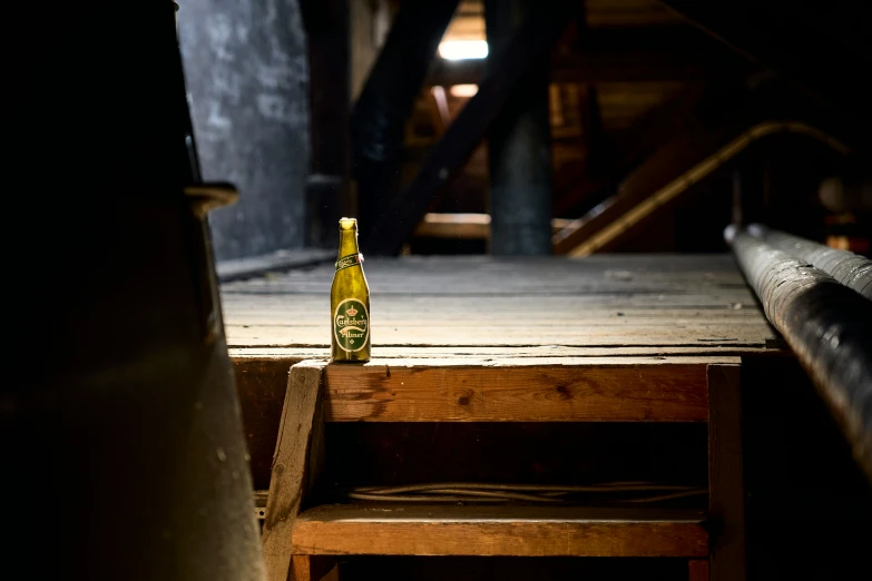 a bottle with beer sitting on a wooden step