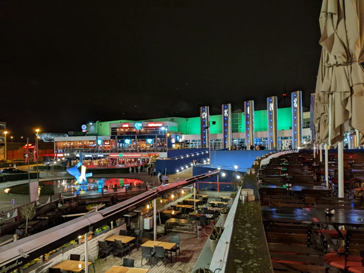 a view of an outdoor dining area at night with lighted restaurants and umbrellas