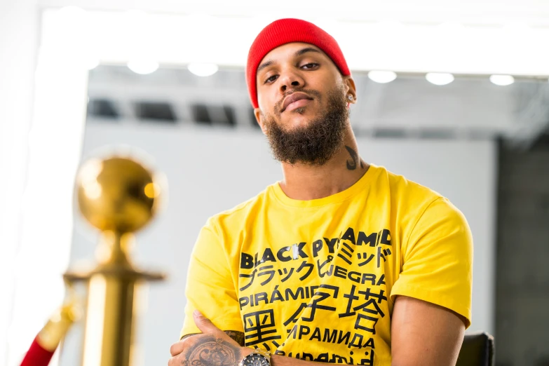 a man with tattoos, yellow shirt and a red hat