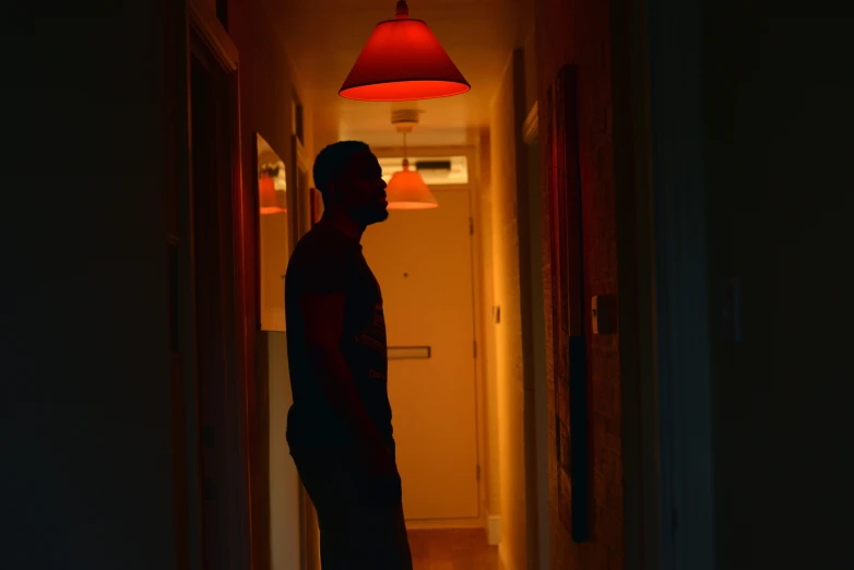 a man looking in a dark room at a lamp