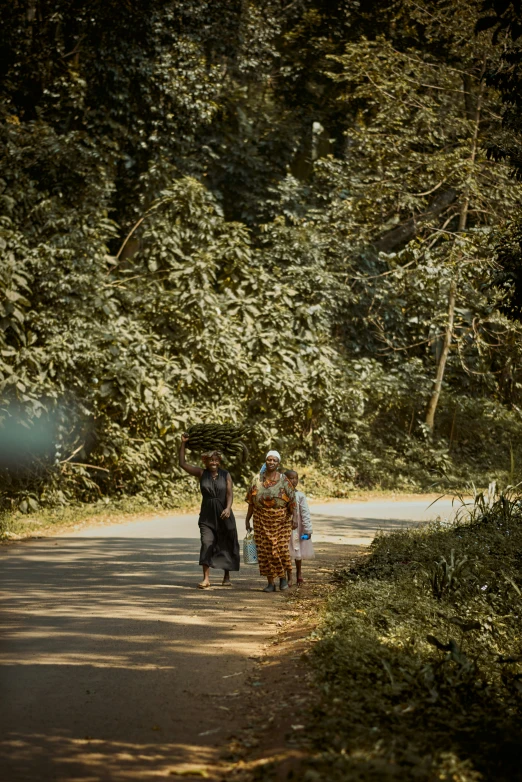 three people walking down the road by some trees