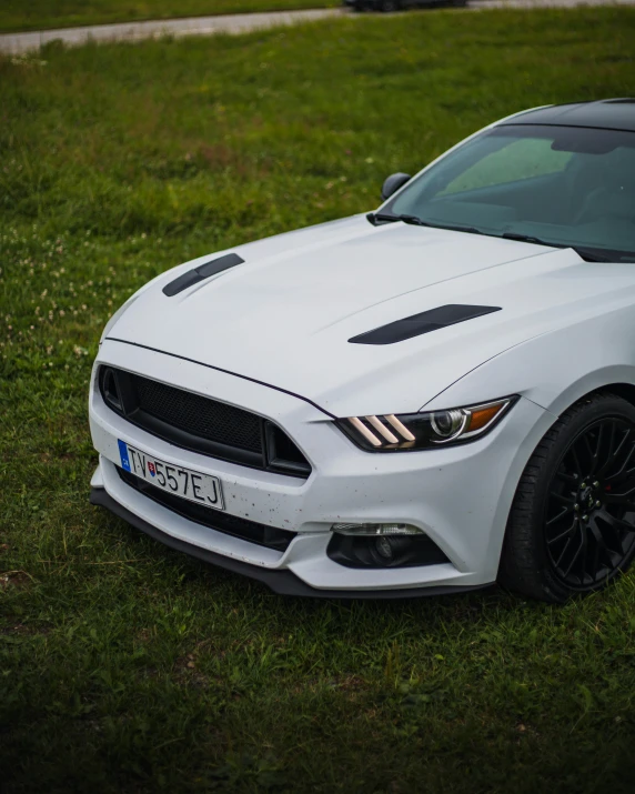 a white mustang car parked on the side of a road