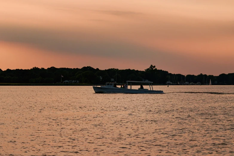 a boat in the ocean at sunset near a forest