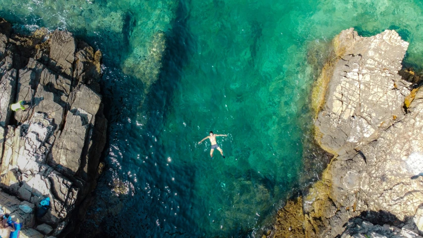 a person floating on the ocean by some rocks