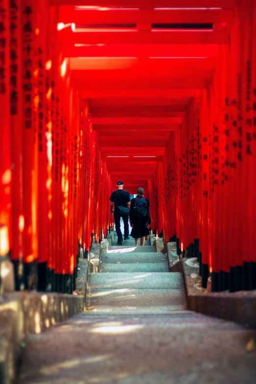 two people are walking down a set of stairs in a tunnel