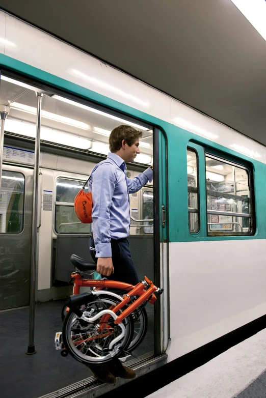 man with orange bicycle standing in train doorway looking at window