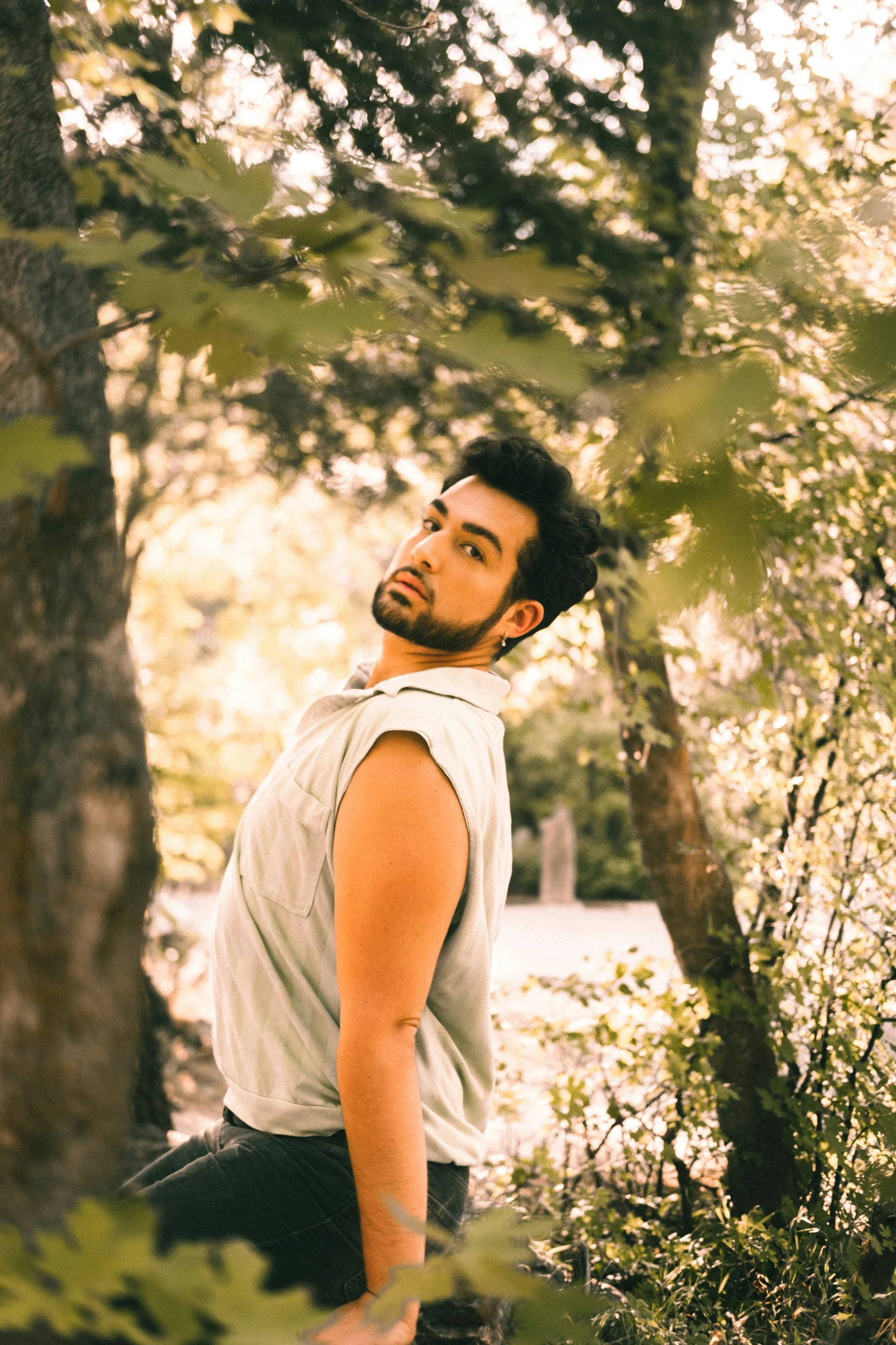 a young man standing amongst the trees in a forest