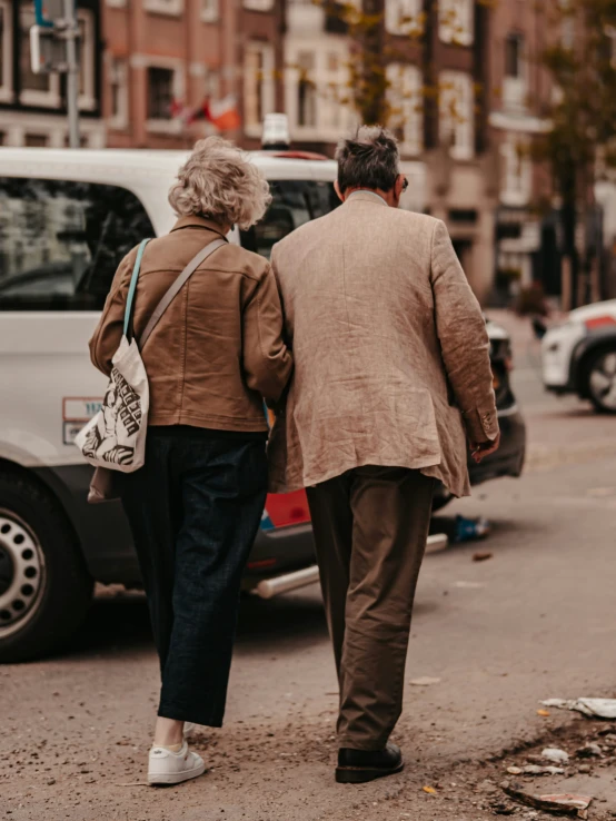 a couple walk down the street past parked cars