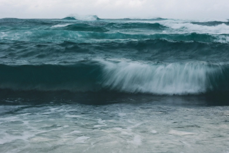 a blue ocean with a large wave coming up from the shore