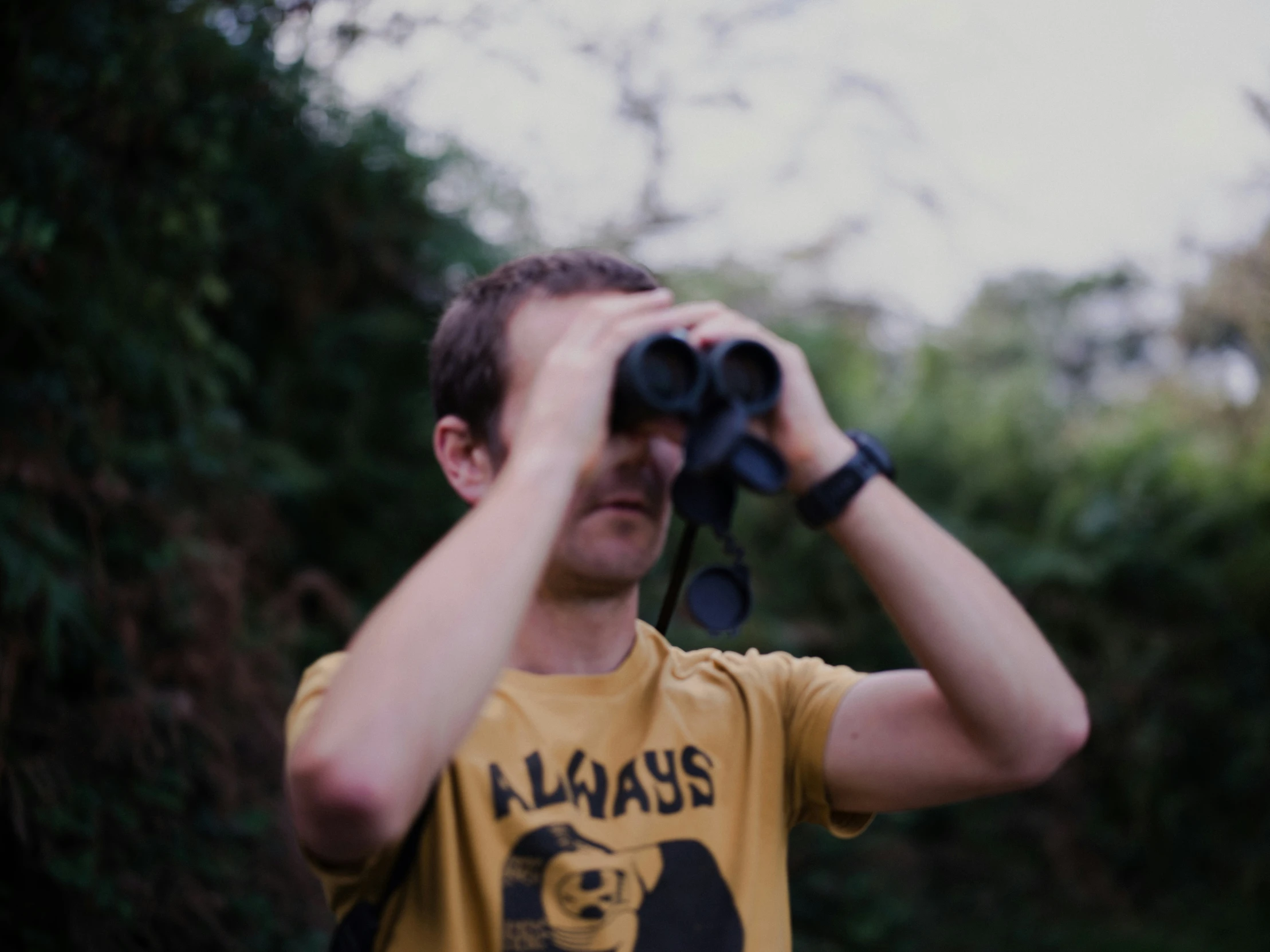 a young man holding binoculars to look into the distance