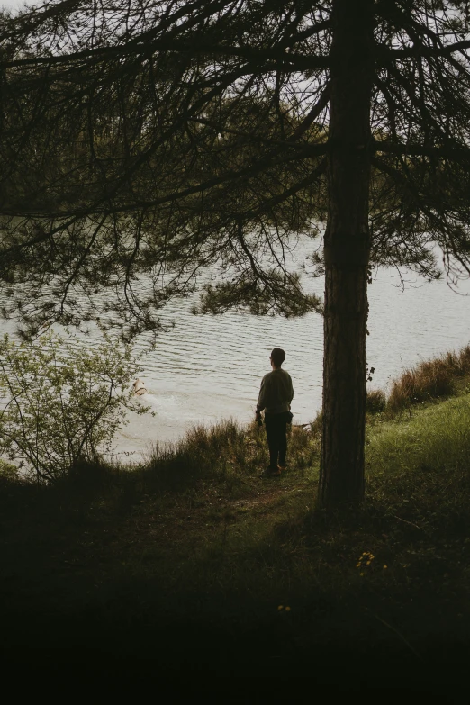 man walking up a hill by a lake