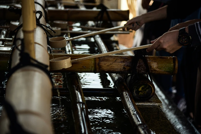 people are weaving wooden poles on a line