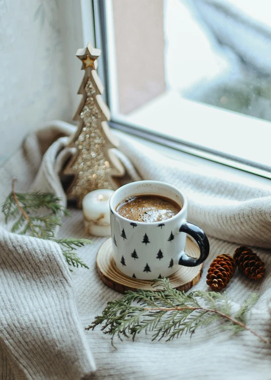 two coffee cups on a saucer with one with a gold tree decoration