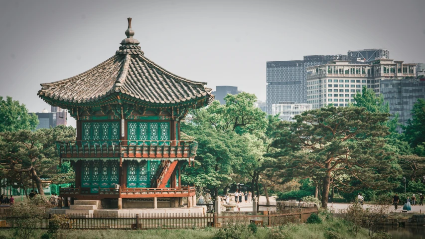 a green and red pagoda in the middle of the park