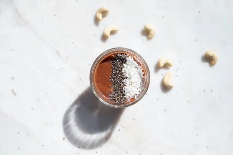 a glass of cocoa on a table with some nuts