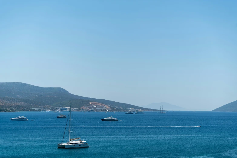 several sail boats are in the water near shore