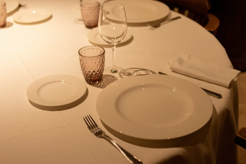 there is a white table with silverware and empty glasses on it