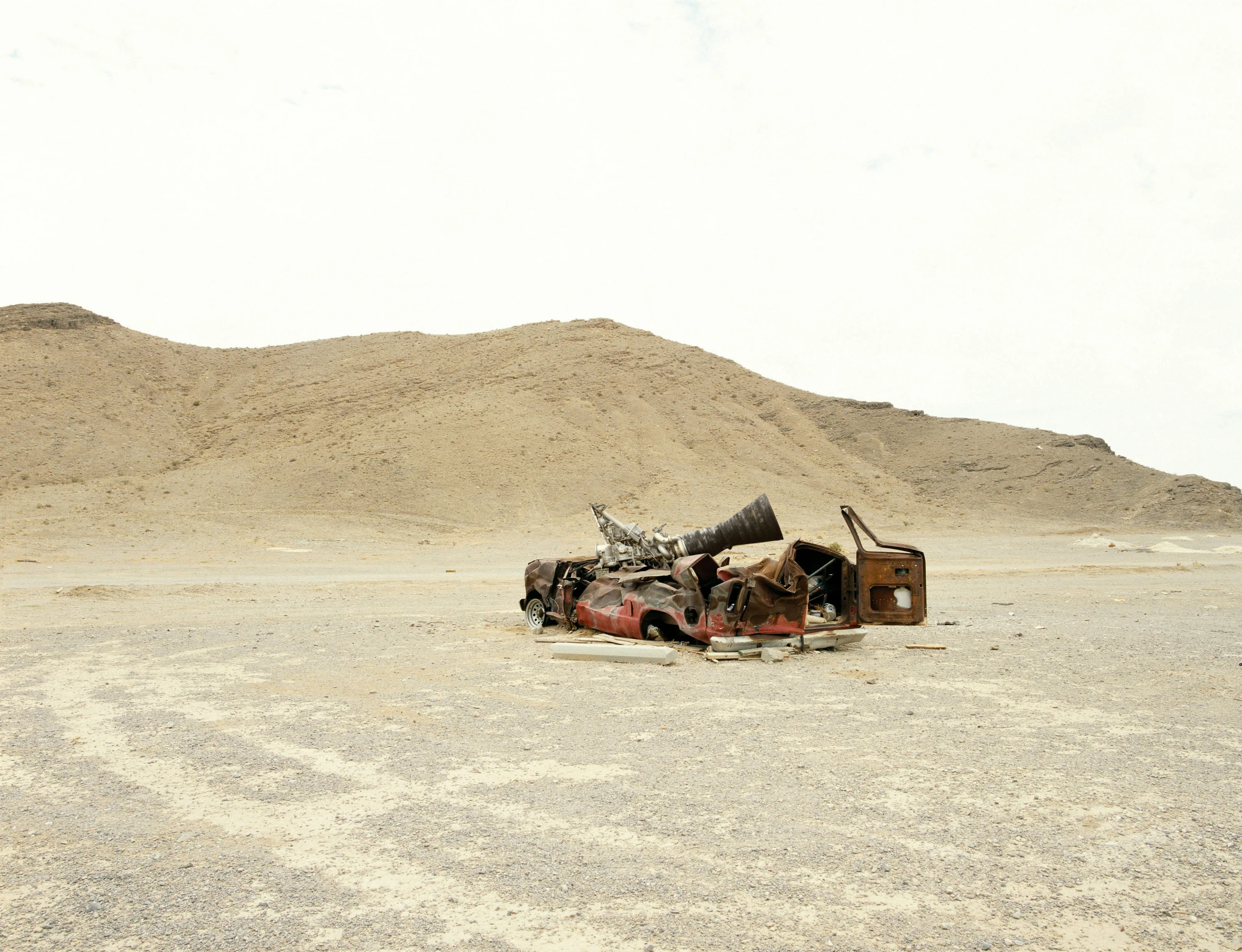 a wrecked car sits in an area filled with sand