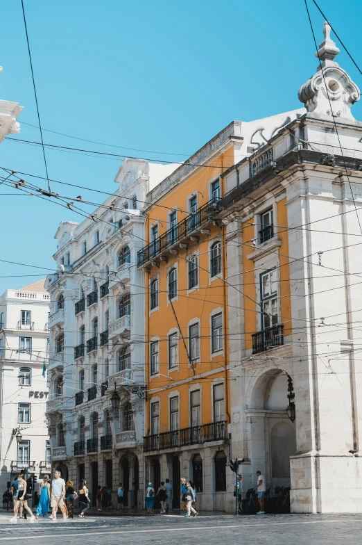 people walking in front of yellow buildings and power lines