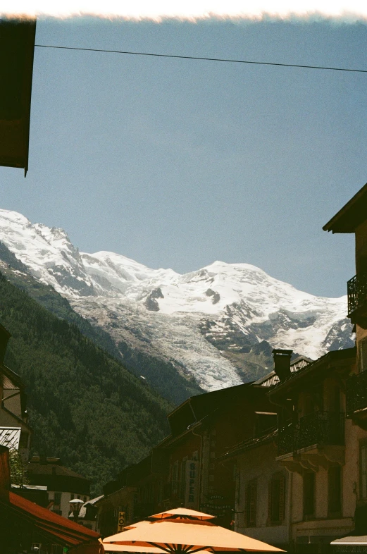 a very tall white snowy mountain behind some buildings