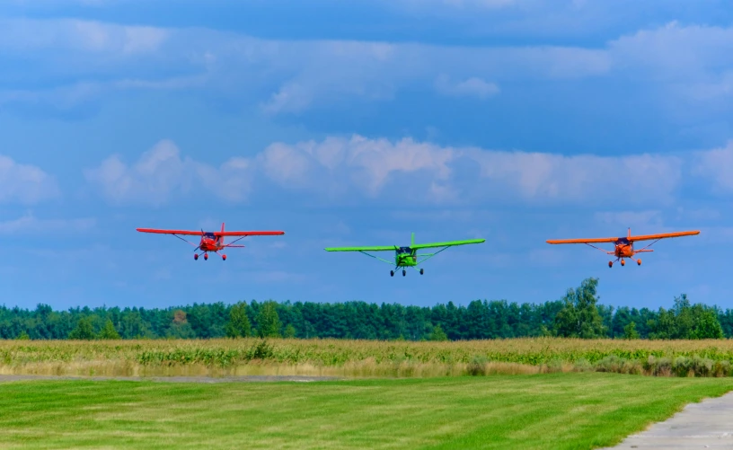 three small planes in flight over an open field