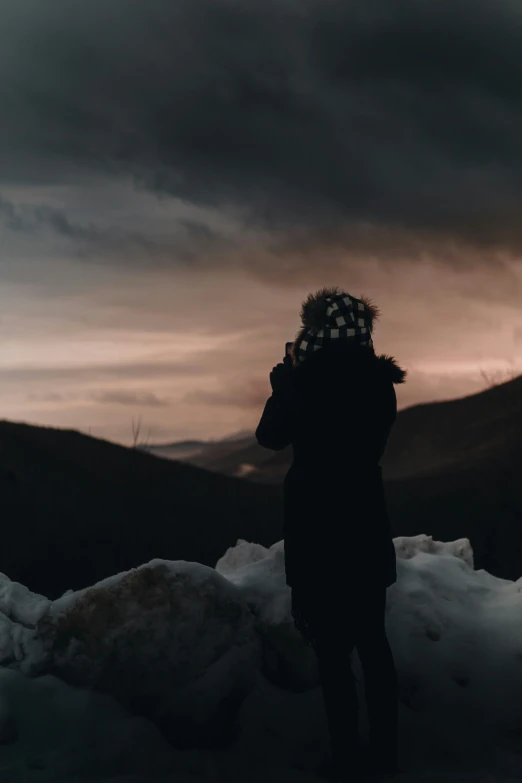 a person standing in the snow at sunset