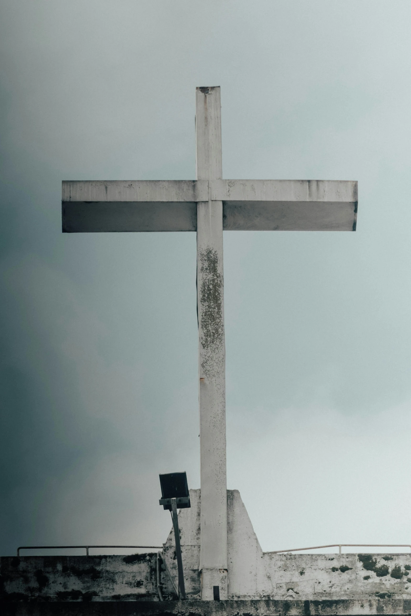 a large cross stands near a building on a cloudy day