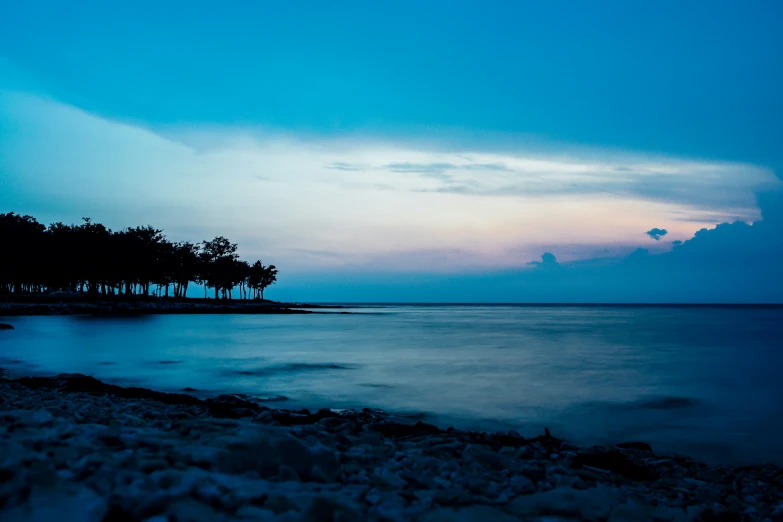 the sun sets over the water in a beach area