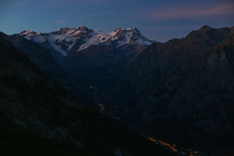 mountains lit up at night with the tops of a mountain in the background