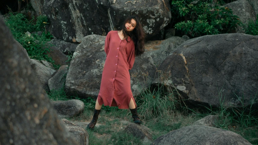 a woman in a red dress posing for a picture by some rocks