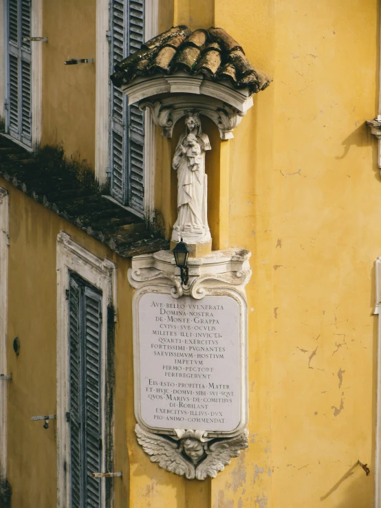 the statue on the yellow building is beside a plaque