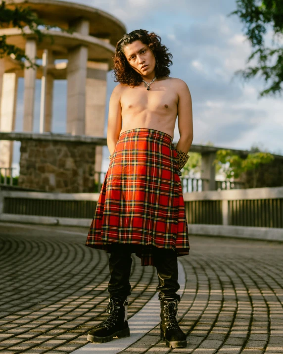 a guy in a kilt standing on a brick walkway