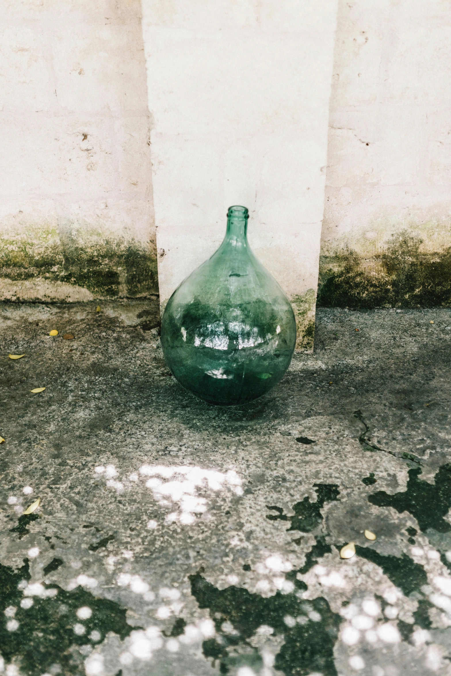 an empty green vase is next to a wall