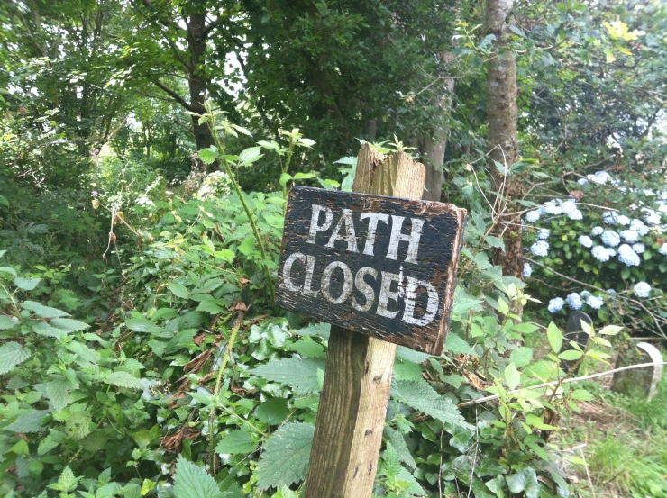 a sign on a wooden post reads, path closed