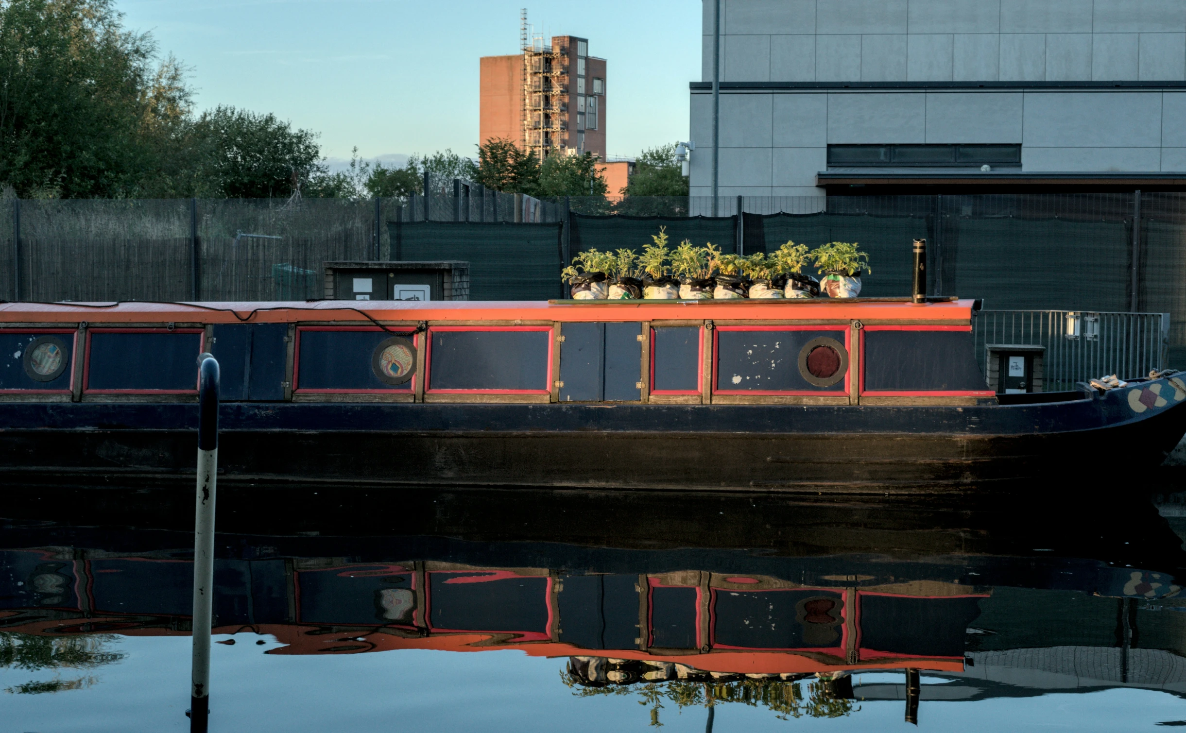 a houseboat with plants on top of it next to a dock