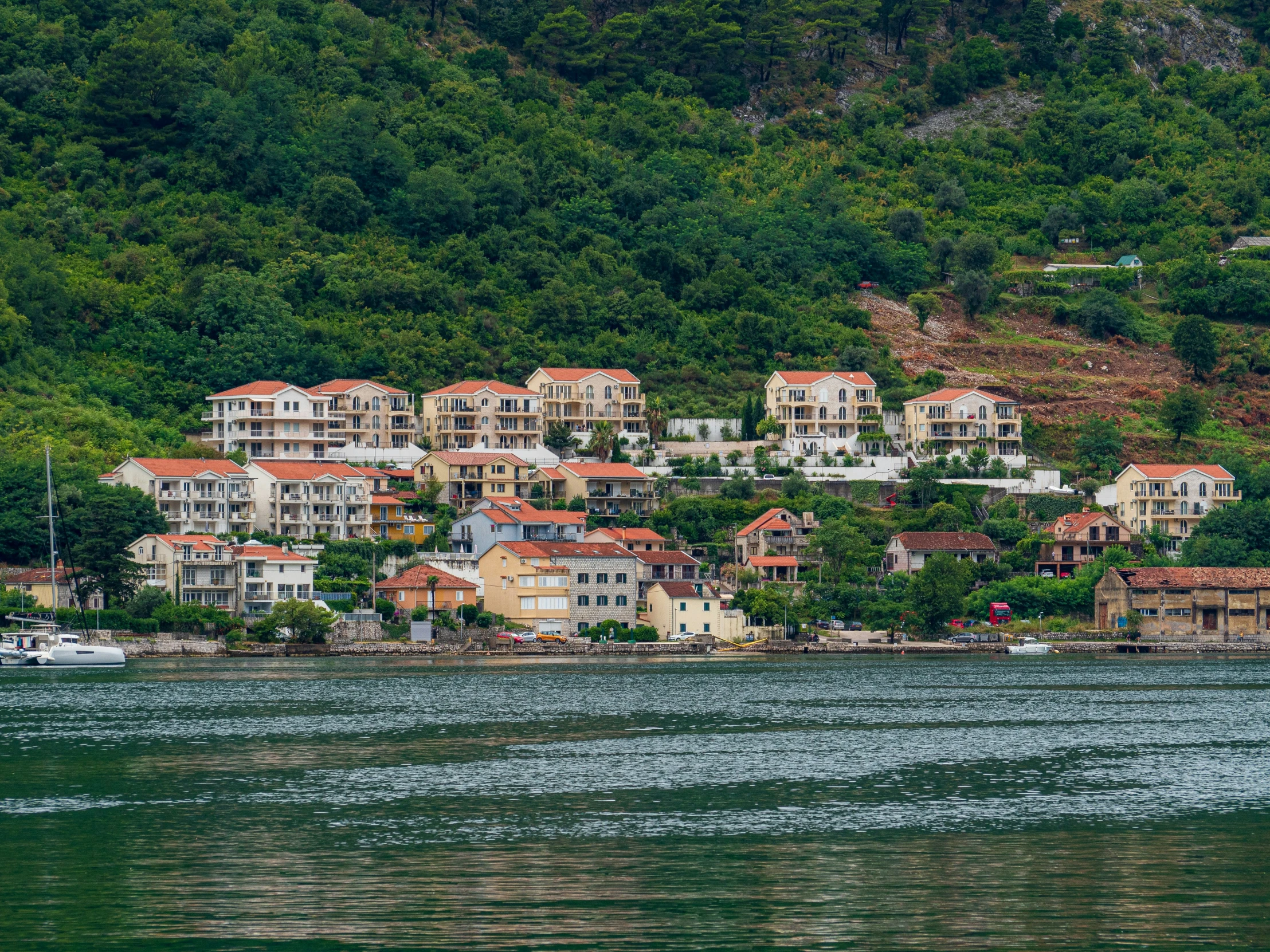 houses sit on top of a hillside above the water