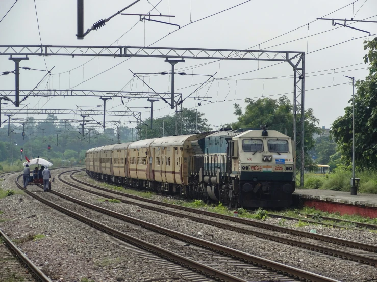 a train riding down the track past people walking