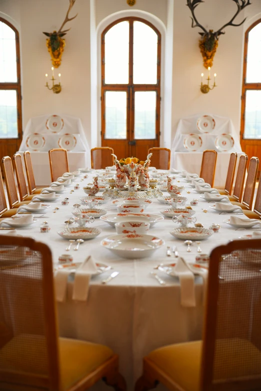 the table is set with place settings for two and a deer heads