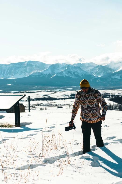 a man walking through a field while holding onto a snowboard