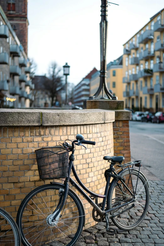 two bikes  to a brick wall on a sidewalk