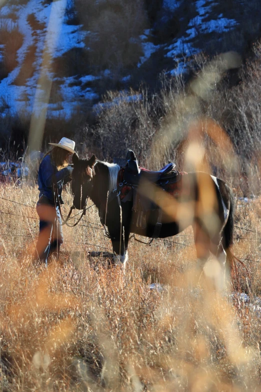 a person in a cowboy hat and boots holding on to a horse