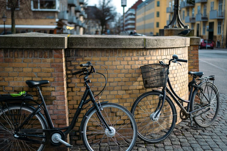 two bikes leaning against a brick wall