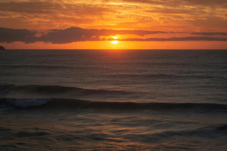 a large body of water with the sun setting in the background