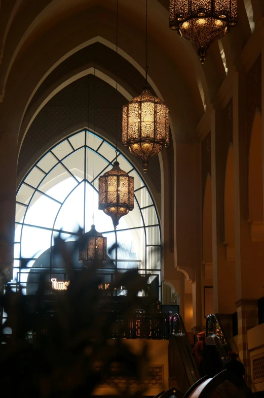 a church with multiple hanging lamps and a large arched window