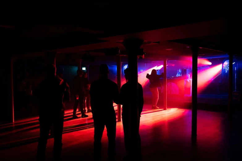 two people standing in a darkened room, the light is brightly colored