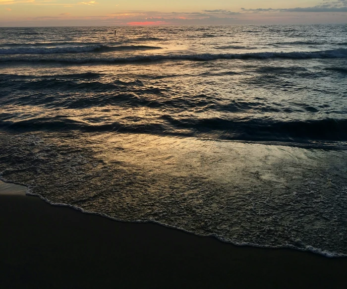 a sandy beach with waves coming towards the shore