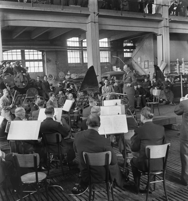 an orchestra plays for their peers in an industrial building