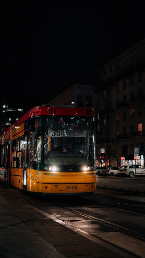 a red and yellow double decker bus in front of a building at night