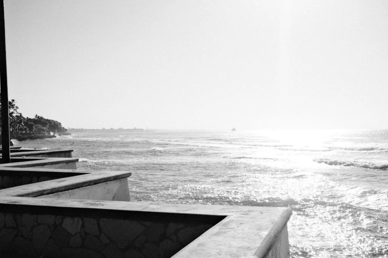 a concrete wall on the edge of a beach near the water