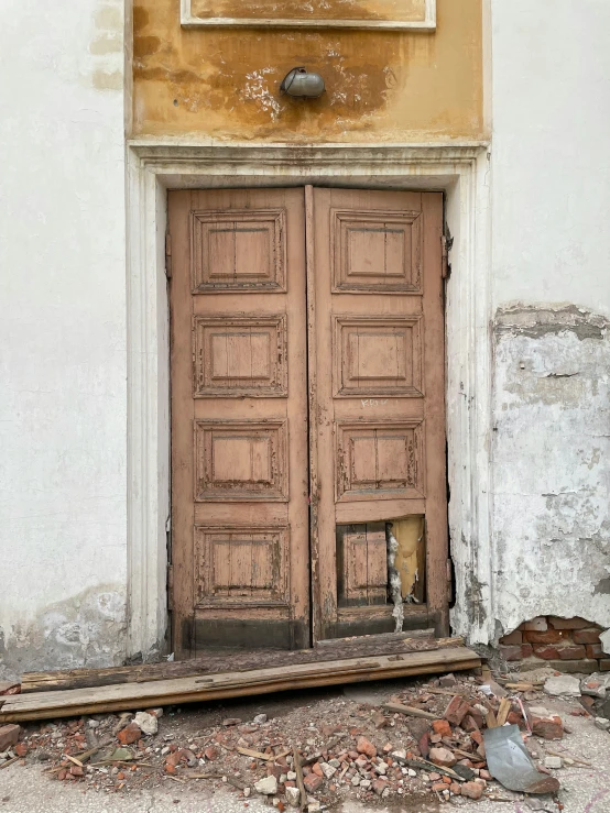 an old double doors is left open in a crumbling house